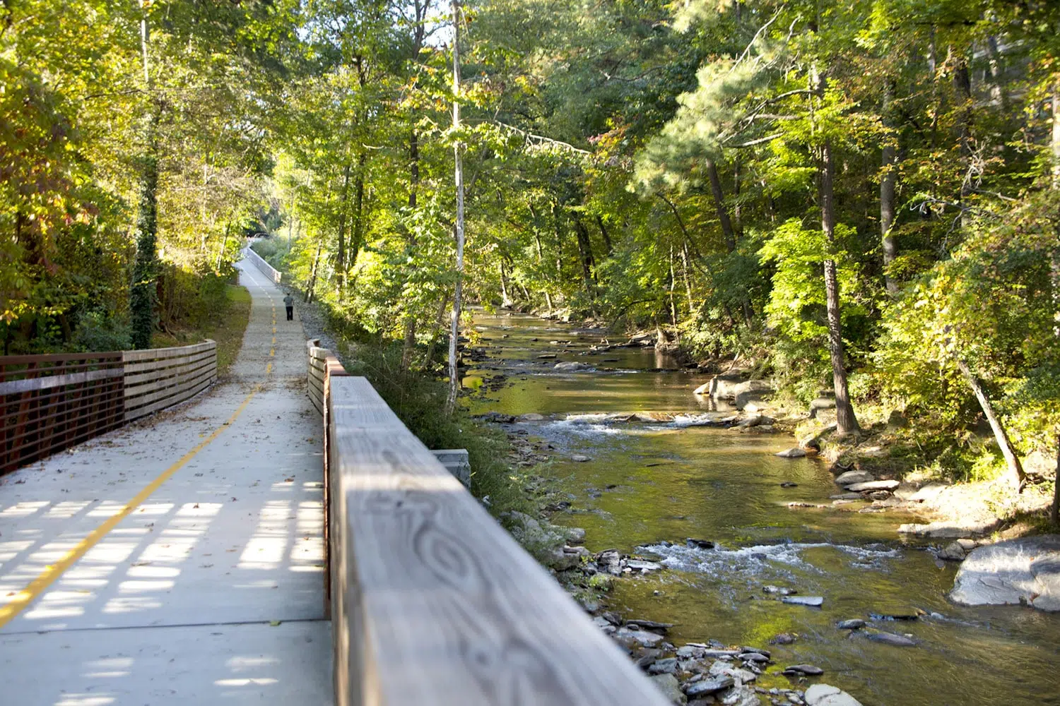The trail runs by a small body of water with trees surrounding the trail.